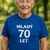 Muž v modrém tričku s nápisem Mladý 70 let, pěkné prostředí v přírodě.