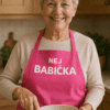 Babička v růžové zástěře s nápisem "Nejlepší babička" připravuje jídlo v kuchyni.