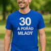 Alt: Pán s potiskem "30 a pořád mladý" na modrém tričku, venku v parku.