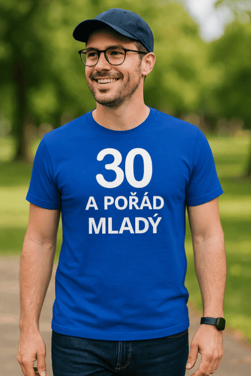 Alt: Pán s potiskem "30 a pořád mladý" na modrém tričku, venku v parku.