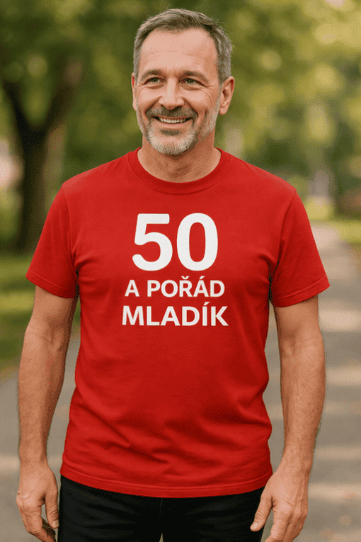 Muž v červeném tričku s nápisem 50 a pořád mladík, outdoorové prostředí, sportovní móda, aktivní stárnutí.