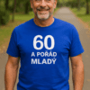 Muži v modrém tričku s nápisem „60 a pořád mladý“ na procházce v parku.
