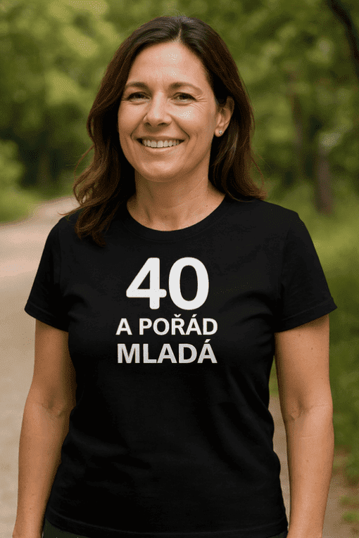 Žena v běžeckém tričku s nápisem "40 a pořád mladá" na procházce v přírodě.