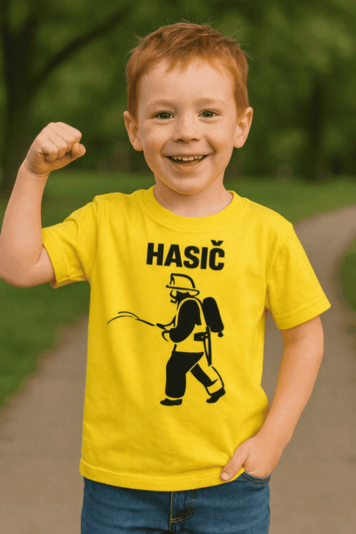 Dítě v žlutém tričku s hasičským motivem, radost a síla, outdoorové prostředí, kluk s výjimečným úsměvem.
