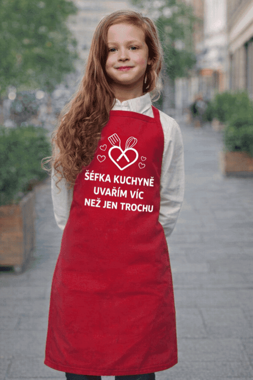 Dívka v červené zástěře s nápisem o vaření více než jen trochu.