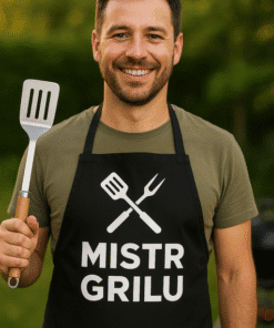 Pohled na muže v černém grilovacím tričku s nápisem MISTR GRILU a kuchyňským náčiním, ideální pro grilování a outdoorové akce.