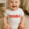 Roztomilé miminko v tričku s nápisem Trouble, veselá dětská fotografie.
