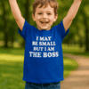 Dítě nosí modré tričko s nápisem "I MAY BE SMALL BUT I AM THE BOSS" a usmívá se s rozpaženýma rukama.