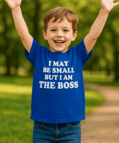 Dítě nosí modré tričko s nápisem "I MAY BE SMALL BUT I AM THE BOSS" a usmívá se s rozpaženýma rukama.