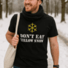 Ombuvalý muž v černé tričku s nápisem Don't eat yellow snow, v zimní přírodě.