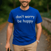 Usměvavý muž v modrém tričku s nápisem don't worry be happy, venku, příroda.